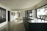 The kitchen is anchored by a large black island, which pops against the crisp white walls and polished concrete floors.